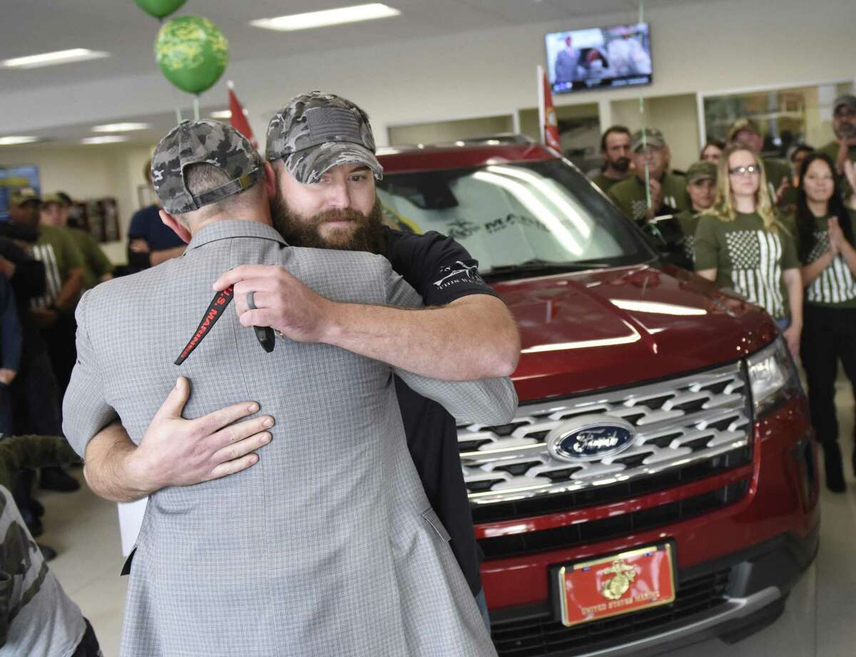 Stamford Ford Lincoln President Dominic Franchella presents U.S. Marine Ret. Cpl. Andrew Burns with a new car during the Veterans Day car giveaway at Stamford Ford Lincoln in Stamford, Conn. Monday, Nov. 12, 2018. The dealership gave away cars to U.S. Marine Ret. Cpl. Andrew Burns and U.S. Army Ret. Col. Vanessa Benson, leader of Ford Military and Veteran Initiatives.
