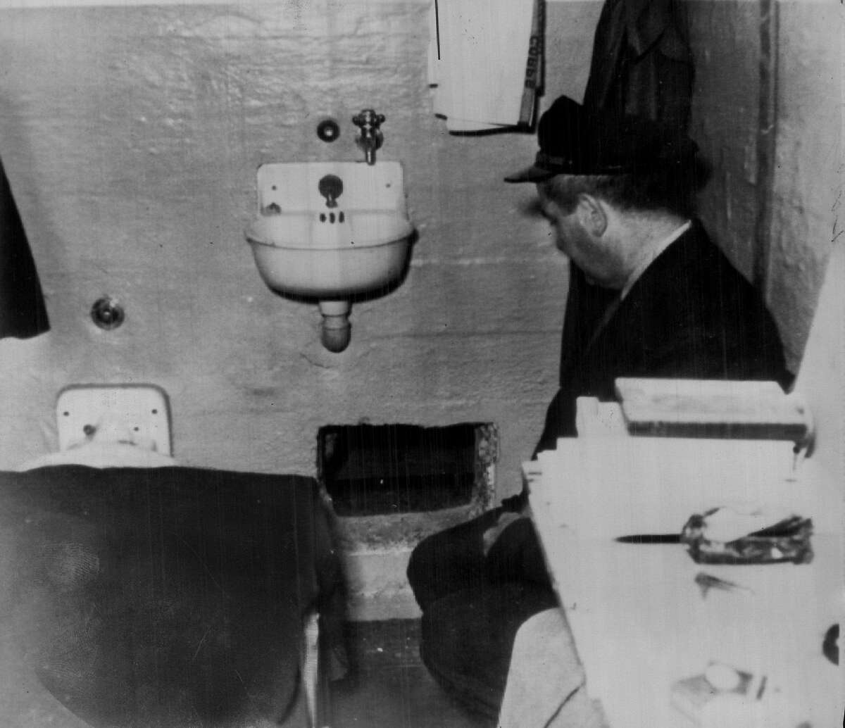 Where the Alcatraz prison break started: A prison guard kneels by hole in Frank Morris' cell.
