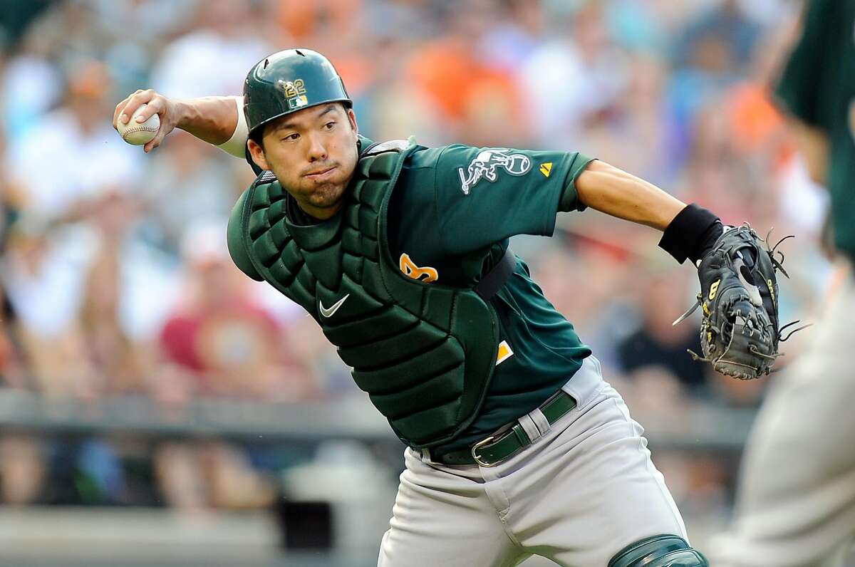BALTIMORE, MD - AUGUST 24: Kurt Suzuki #22 of the Oakland Athletics fields a bunt and throws to first base in the eighth inning against the Baltimore Orioles at Oriole Park at Camden Yards on August 24, 2013 in Baltimore, Maryland. (Photo by Greg Fiume/Getty Images)