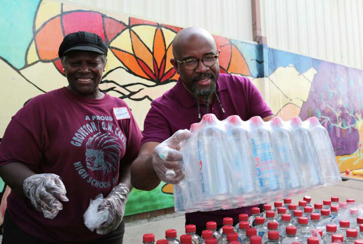 Pastor Rudy Rasmus hands out packs of bottled water at St. John’s United Methodist Bread of Life facility where they offer food to the hungry.
