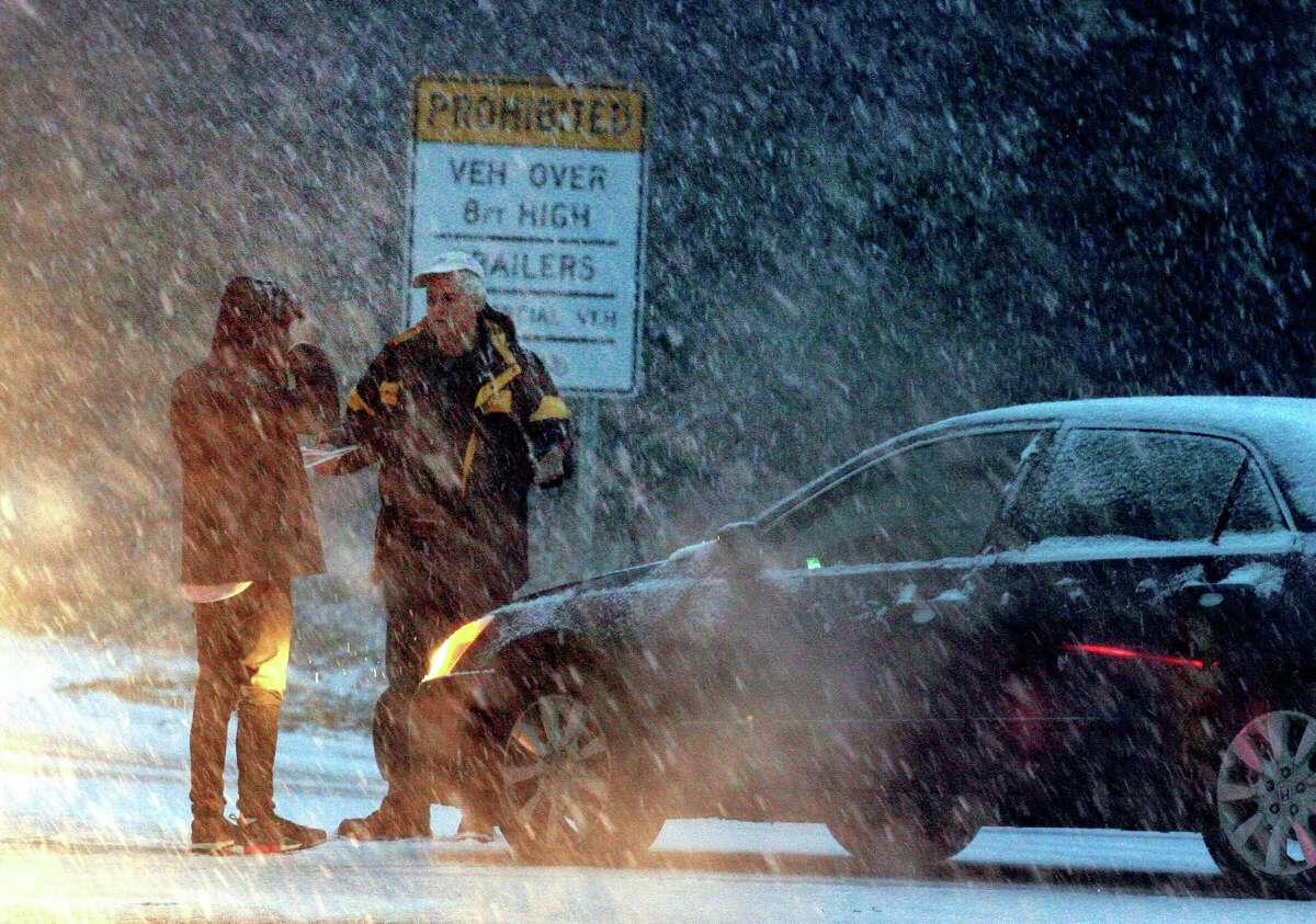 As heavy snow falls, two drivers talk after a minor accident at the entrance to the Merritt Parkway at Park Ave in Trumbull, Conn., on Thursday, Nov. 15, 2018. The snow which started falling in the later afternoon, caused many cars to be stuck along Park Ave and other roads around the area.