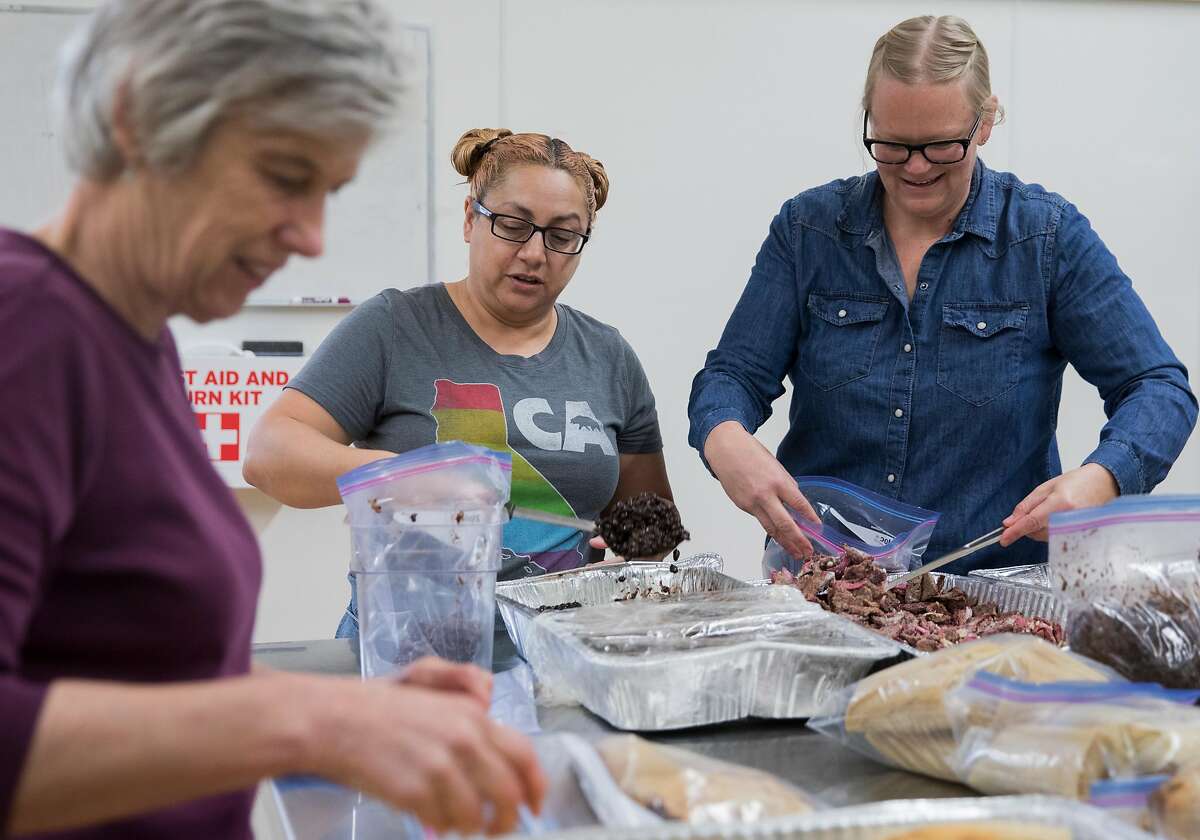 (From left) Berkeley Food Network employees Syliva Del Toro, Susan Choy and Sarah Palmer Frank repackage food leftover from a local restaurant to be stored and given to homeless shelters while working at Bauman College in Berkeley, Calif. Thursday, Nov. 15, 2018.