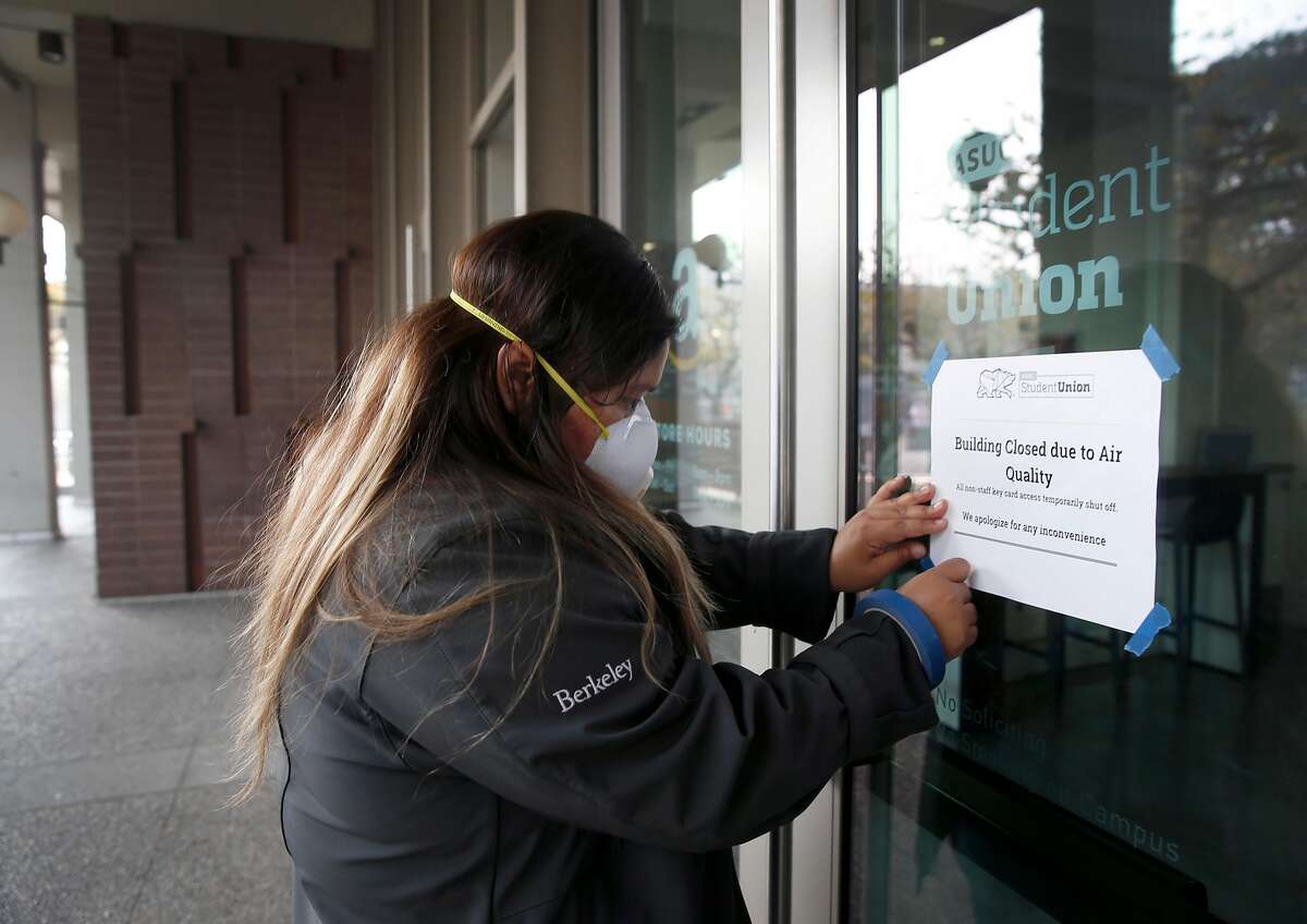 Chelsea Lopez tapes a notice to an entrance of the Student Union announcing the building?•s closure at UC Berkeley on Friday, Nov. 16, 2018. University officials cancelled classes Friday because of the unhealthy air conditions which continue to choke the Bay Area with heavy smoke from the Camp Fire in Butte County.