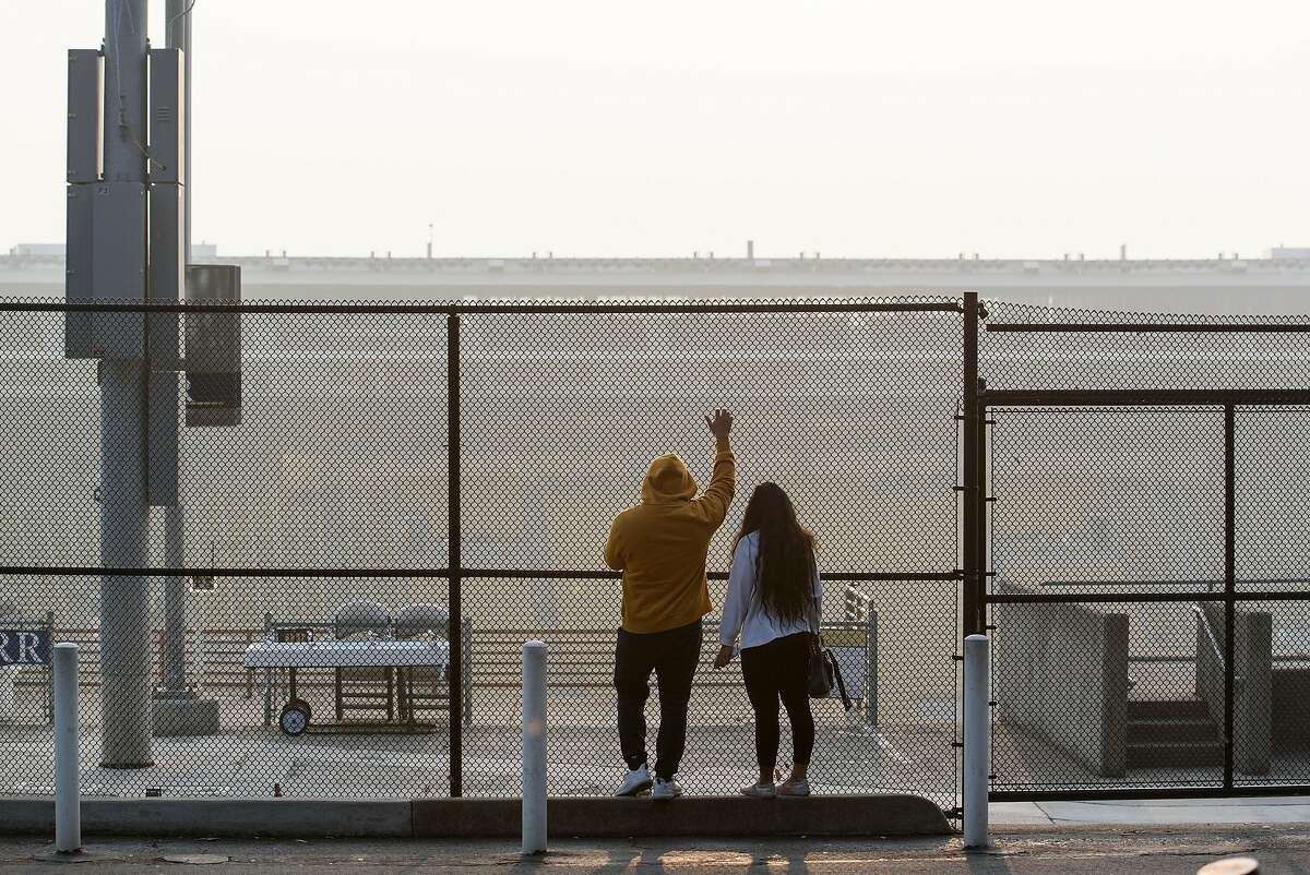 Two people look out over a hazy Memorial Stadium following an announcement that the "Big Game" versus Stanford University over the weekend is canceled due to poor air quality, in Berkeley, California, on Friday, November 16, 2018.