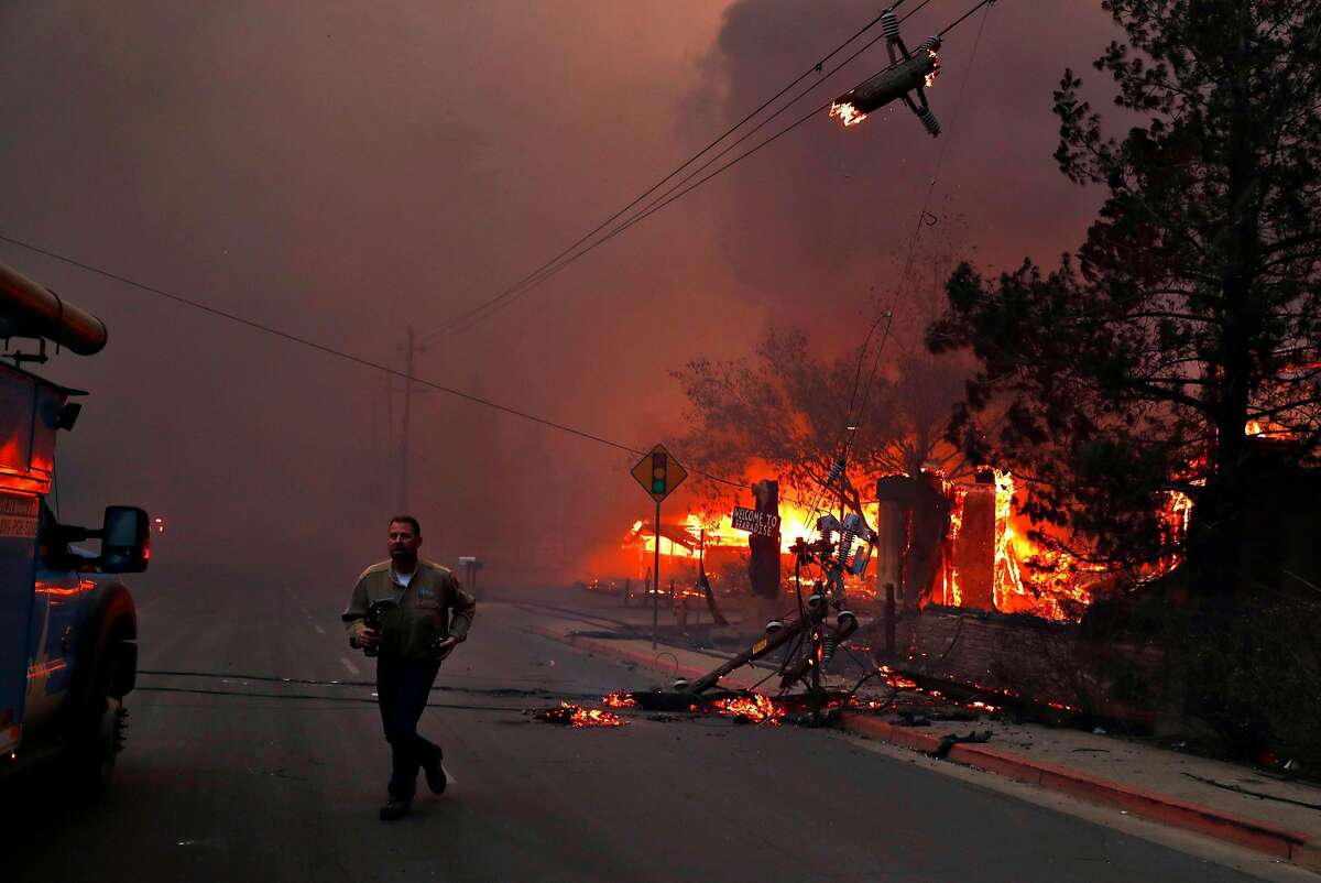 A PG&E worker runs while dealing with downed power lines during Camp Fire in Paradise, Calif.. on Thursday, November 8, 2018.