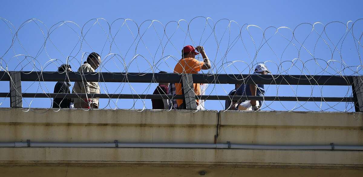 Deportees walk along the U.S. military installed concertina wire installed on the rails of the Juarez-Lincoln International Bridge on Friday, Nov. 16, 2018 as the military reinforces the border and ports of entry in Laredo, Texas.
