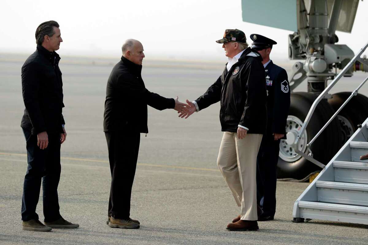 President Donald Trump greets California Gov. Jerry Brown as Gov.-elect Gavin Newsom, left, watches as he arrives on Air Force One at Beale Air Force Base for a visit to areas impacted by the wildfires, Saturday, Nov. 17, 2018, at Beale Air Force Base, Calif.