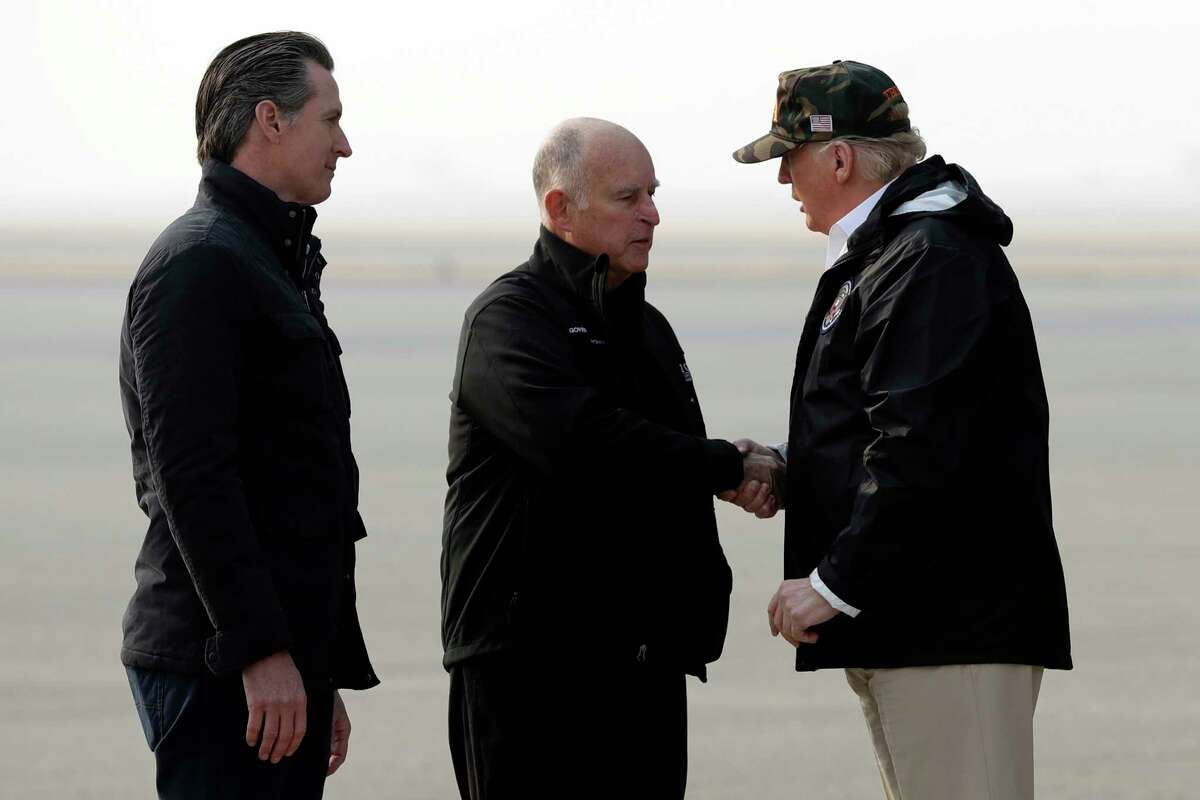 President Donald Trump greets California Gov. Jerry Brown as Gov.-elect Gavin Newsom, left, watches as he arrives on Air Force One at Beale Air Force Base for a visit to areas impacted by the wildfires, Saturday, Nov. 17, 2018, at Beale Air Force Base, Calif.