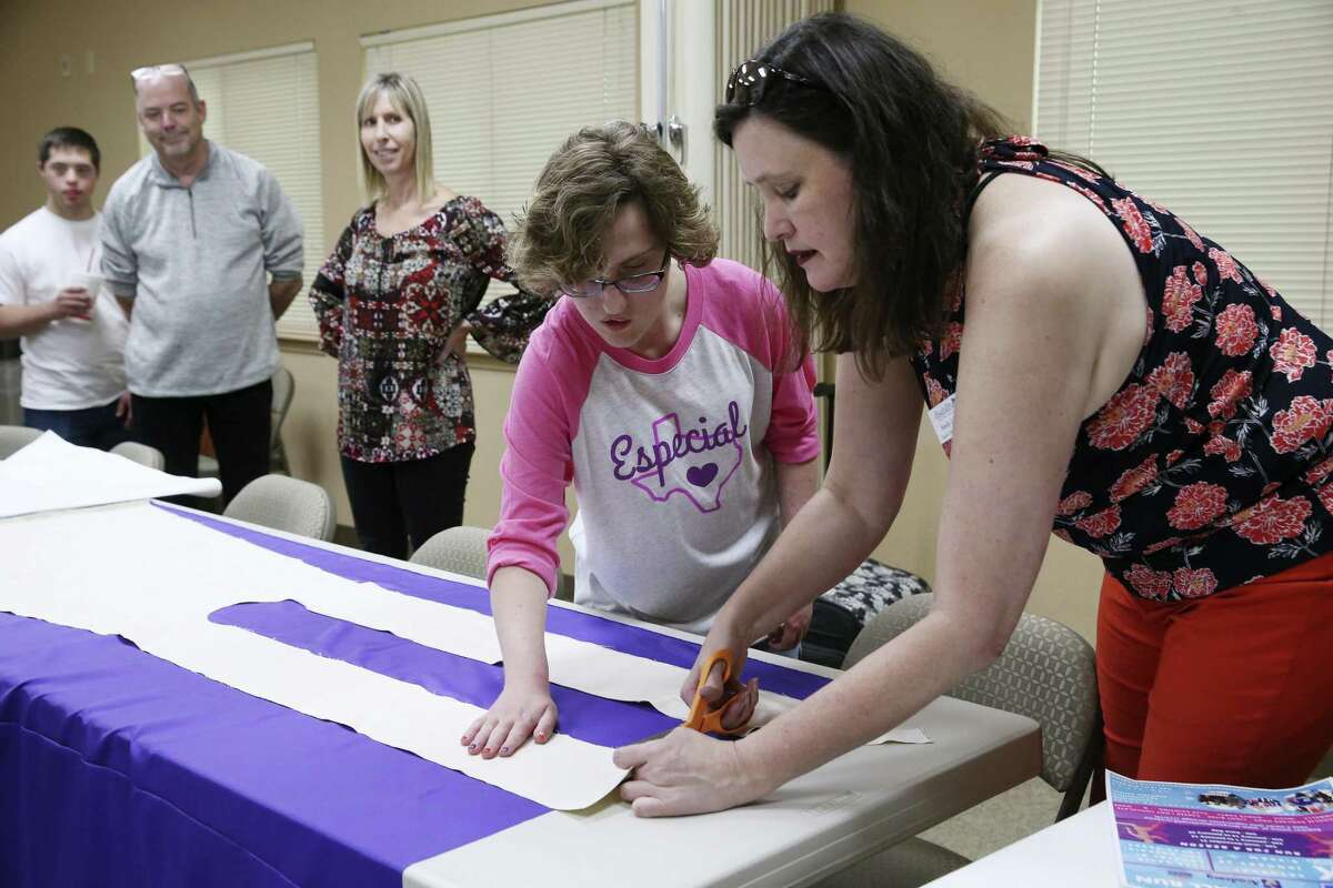 Sandy Liwang, right, demonstrates how to cut a pattern with help from Emma Barron, 20, at a cape-making workshop at Abiding Presence Lutheran Church.