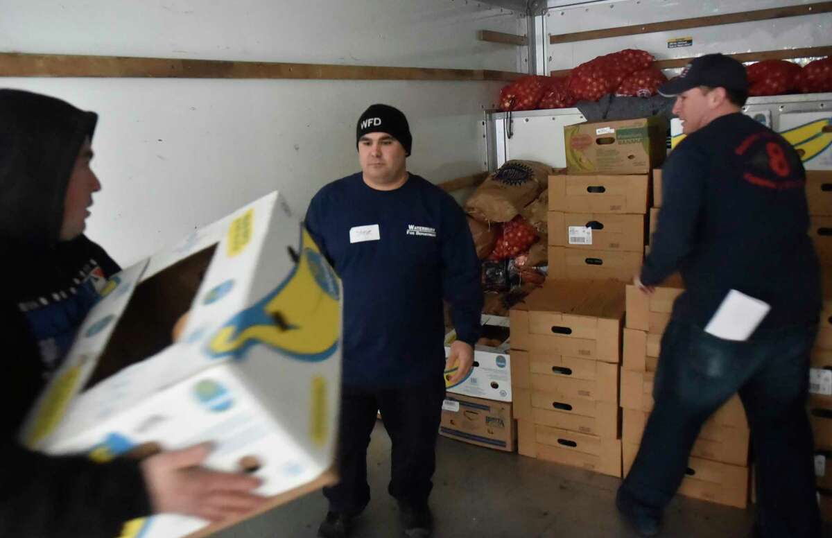 Wallingford, Connecticut - November 19, 2018: Waterbury firefighter Steve Miele, center, with Captain Patrick Maloney, right, are among the volunteers that help fill community food program Thanksgiving orders and load the food orders in vehicles Monday at the Connecticut food Bank in Wallingford for Connecticut Food Bank member agencies.