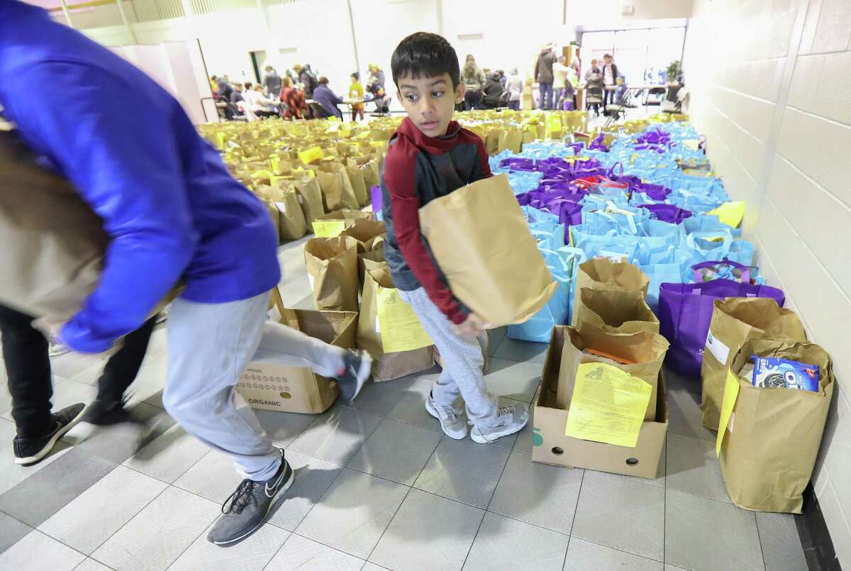 Dilan Dalal, 11, carries bags of food at the East Spring Branch Food Pantry Tuesday, Nov. 20, 2018, in Houston. The food pantry served at least 1,000 families a Thanksgiving meal on Tuesday morning. The pantry provided a turkey (or chicken), a large bag of produce, and bags of non-perishable food to hundreds of families in need.