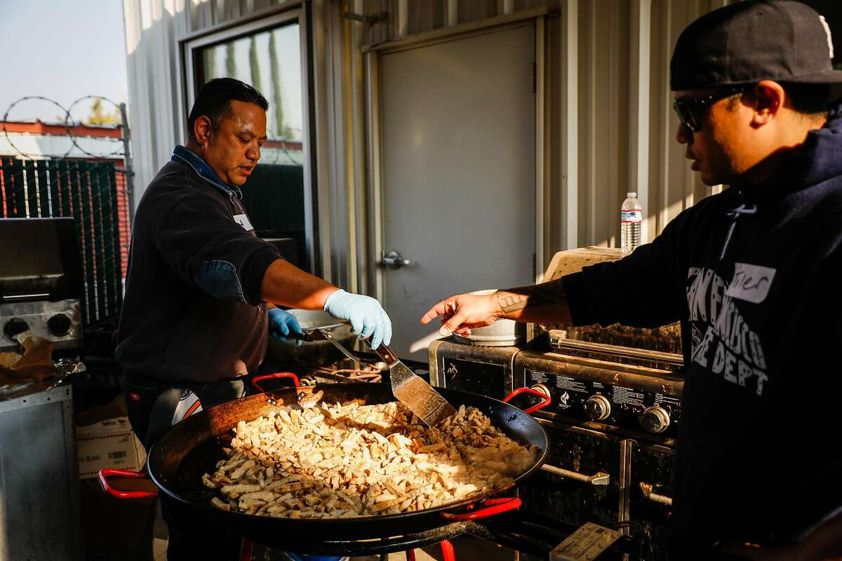 Volunteers John Tuiasosopo (left) and son Tyler Tuiasosopo prepare food for those who were affected and displaced by the Camp Fire in Chico, California, on Tuesday, Nov. 20, 2018.