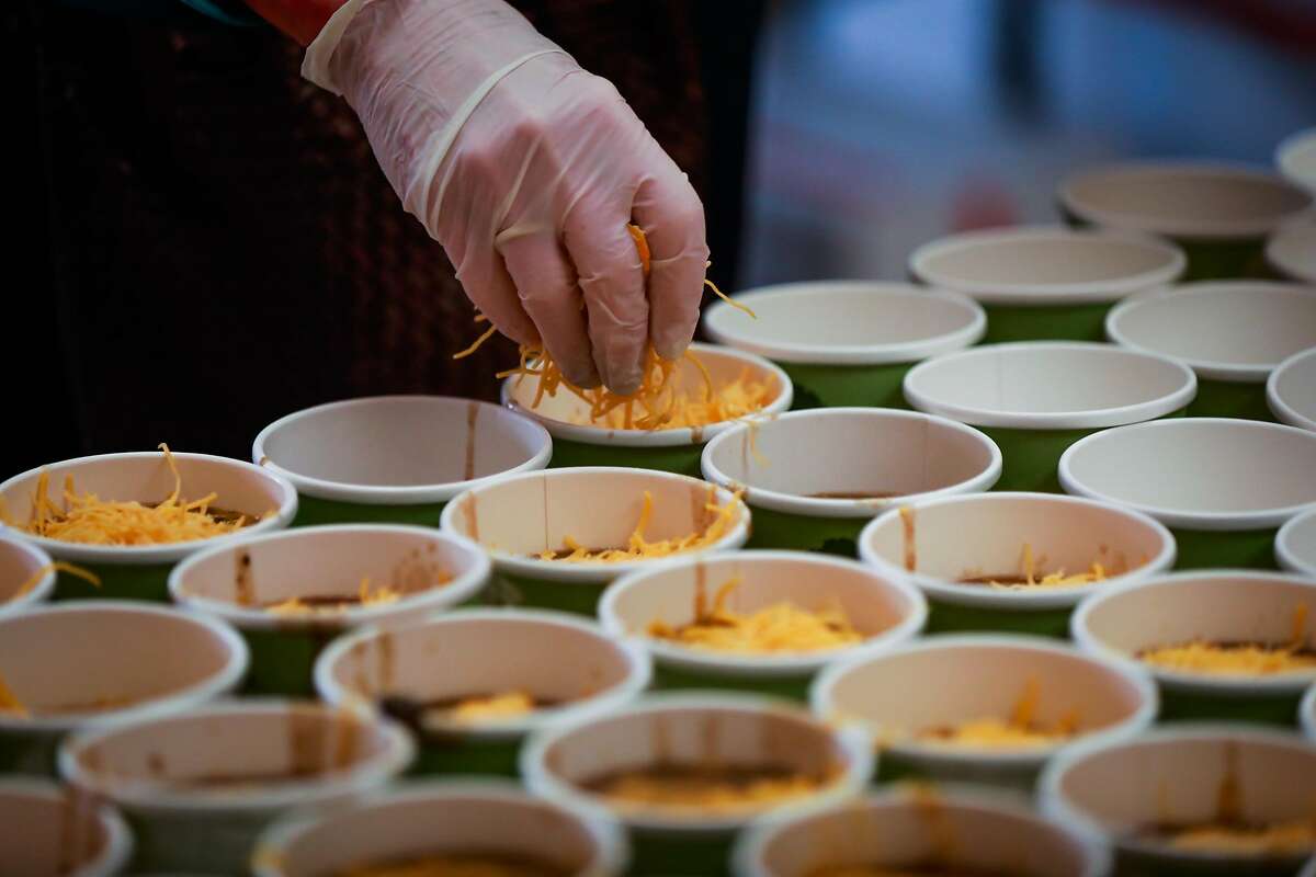 A volunteer pours cheese onto chili as she prepares food for those who were affected and displaced by the Camp Fire in Chico, California, on Tuesday, Nov. 20, 2018.