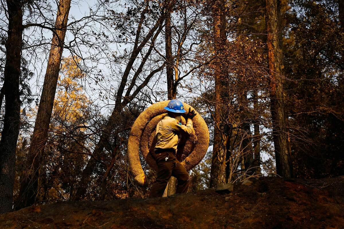 A California Conservation Core member carries up material to help block flooding after the Camp Fire in Paradise, California, on Tuesday, Nov. 20, 2018.
