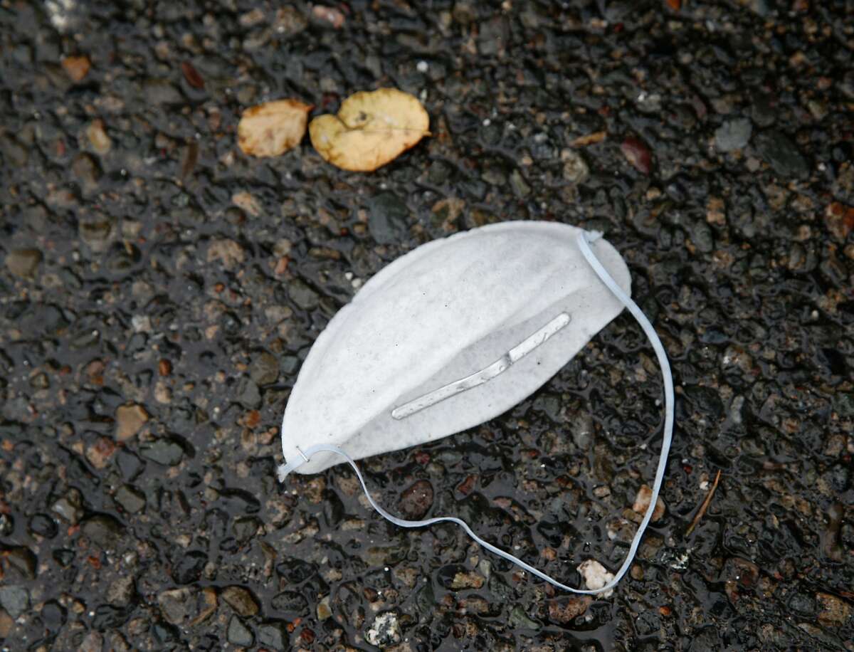No longer needed, a breathing mask is discarded on wet pavement during the first significant rainstorm of the season in Berkeley, Calif. on Wednesday, Nov. 21, 2018.