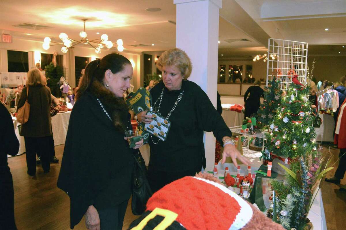 Lynn Carmichael, left, and Julie Williamson, both of New Canaan, discuss a purchase at the preview party for the New Canaan Artisans’ annual Holiday Boutique, hosted at the Roger Sherman Inn in New Canaan on Nov. 16.