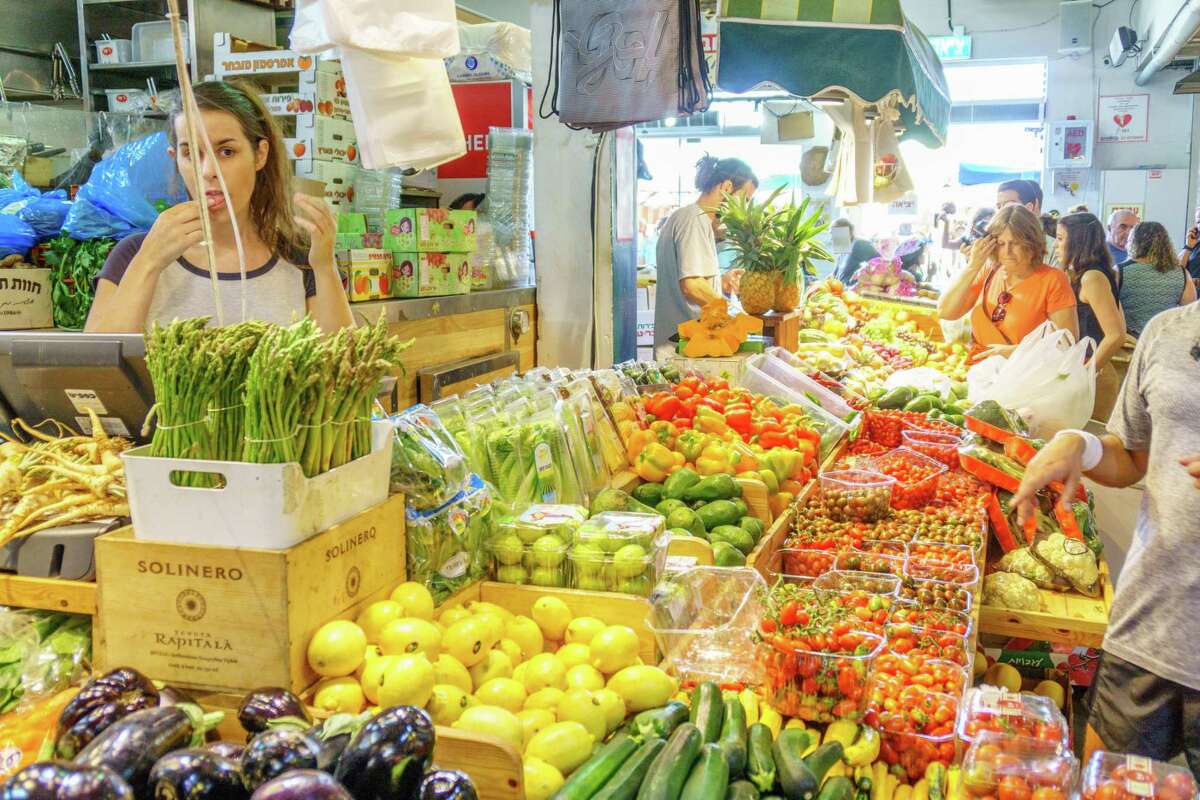 People shop at a fresh fruit stall in a Tel Aviv market.