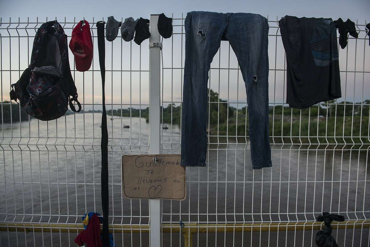 Clothes belonging to a Honduran migrant hangs to dry on the fence of a border bridge that stretches over the Suchiate River, connecting Guatemala and Mexico, in Tecun Uman, Guatemala, Monday, Oct. 22, 2018. Hundreds of migrants, who are part of a caravan bound for the U.S.-Mexico border are waiting on the border bridge to be attended by Mexican immigration authorities. U.S. President Donald Trump says the U.S. will begin "cutting off, or substantially reducing" aid to Guatemala, Honduras and El Salvador over the migrant caravan heading to the U.S. southern border. (AP Photo/Oliver de Ros)