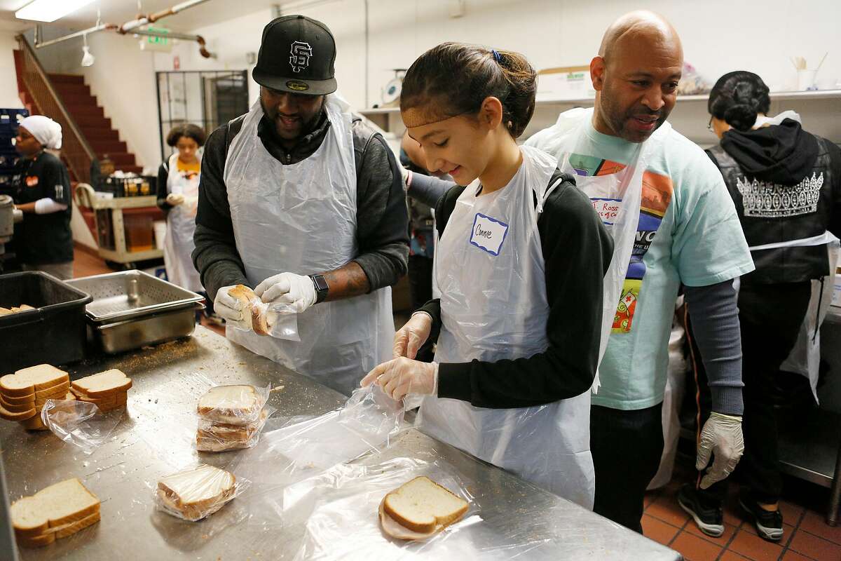 From left: Volunteers Lionel Stevens, Connie Rutherford, 14, and Jason Ross prepare sandwiches for those in need at Glide Memorial Church on Thursday, Nov. 22, 2018, in Oakland, Calif. Glide hosted a Thanksgiving meal for those in need.