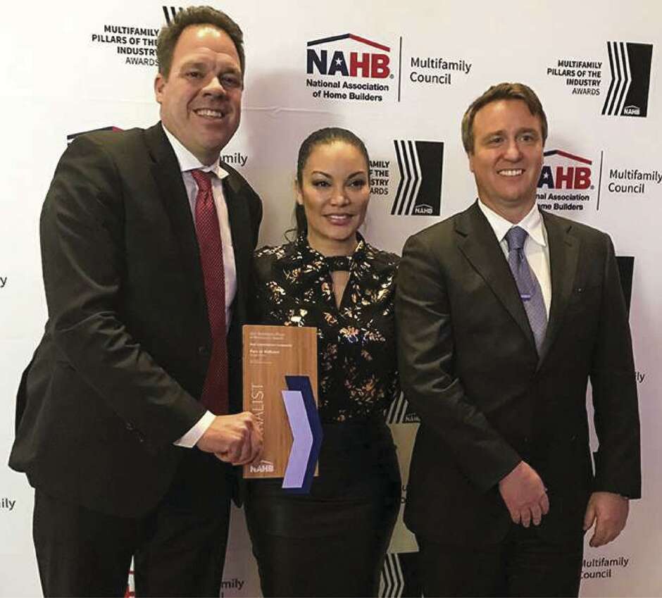 Ben Lemieux, chairman of Surge Homes, left, and Louis Conrad, president of Surge Homes, right, are congratulated by NAHB Awards emcee Egypt Sherrod.