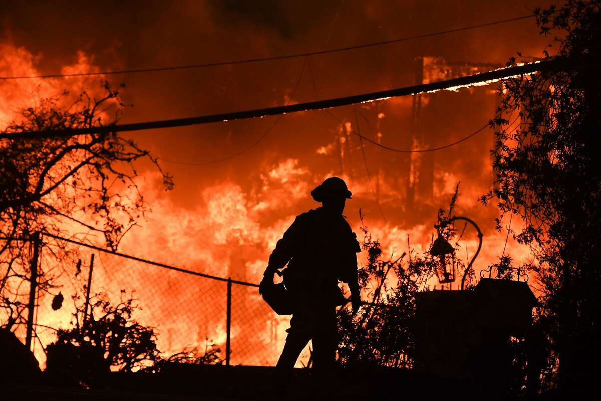 (FILES) In this file photo taken on November 9, 2018, a firefighter is silhouetted by a burning home along Pacific Coast Highway (Highway 1) during the Woolsey Fire in Malibu, California. - Climate change is already hurting the US and global economies and its effects will get worse unless more drastic action is taken to cut carbon emissions, a major US government report warned on Friday, November 23, 2018. "Without substantial and sustained global mitigation and regional adaptation efforts, climate change is expected to cause growing losses to American infrastructure and property and impede the rate of economic growth over this century," said the latest edition of the National Climate Assessment. (Photo by Robyn Beck / AFP)ROBYN BECK/AFP/Getty Images