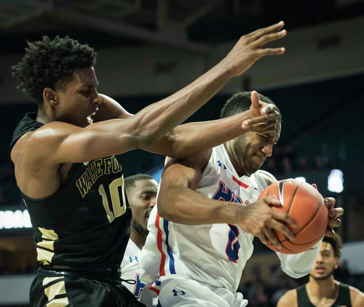 Houston Baptist guard Ian DuBose, right, grabs a rebound over Wake Forest forward Jaylen Hoard, left, in the second half of an NCAA college basketball game Friday, Nov. 23, 2018, in Winston-Salem, N.C. (Allison Lee Isley/The Winston-Salem Journal via AP) 
