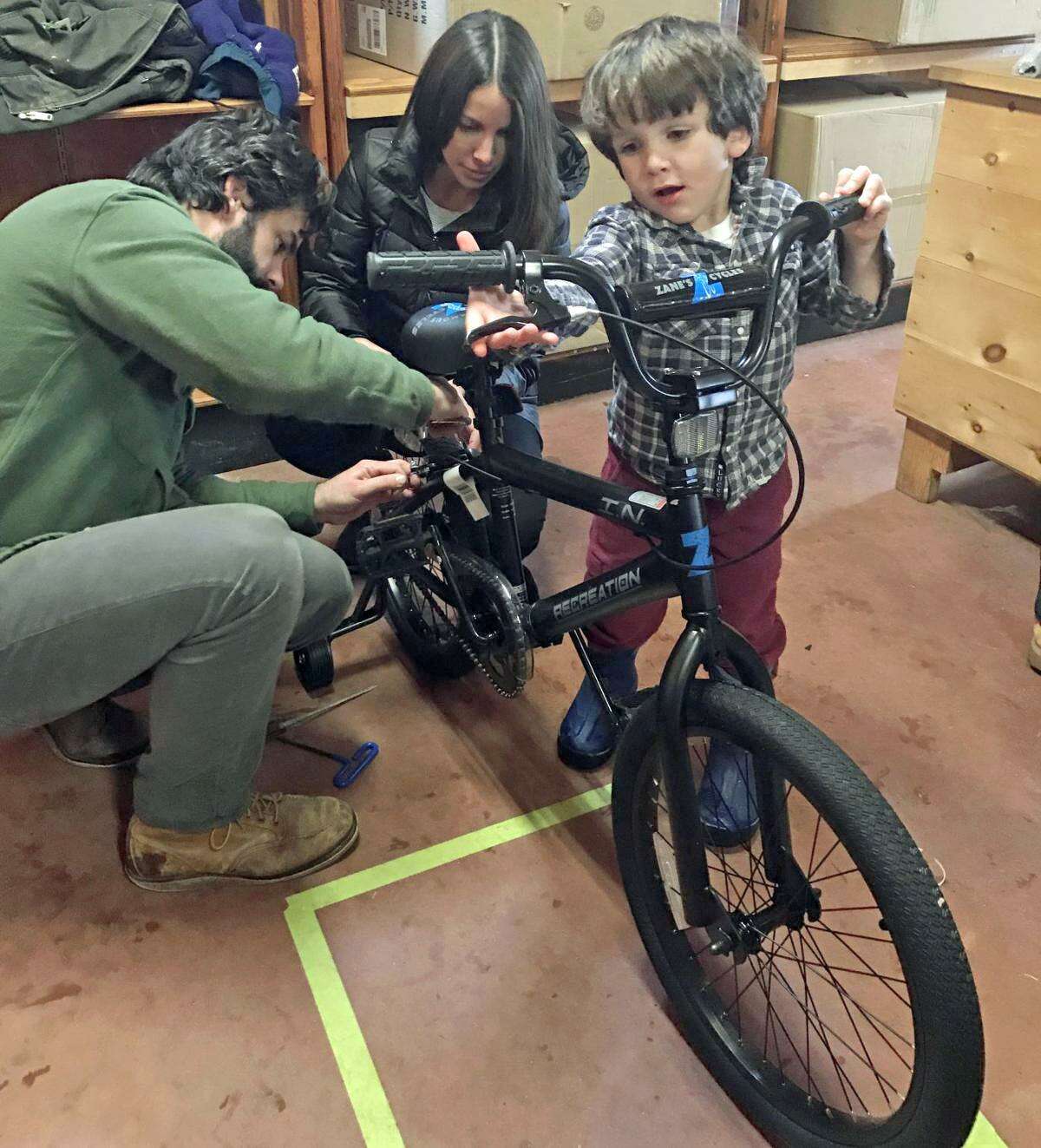 Guilford residents Tom and Maggie Ferrell, with the assistance of their 4-year-old son Bruen, assemble a bike during the 2017 Wishing Wheels Holiday Bike Drive.