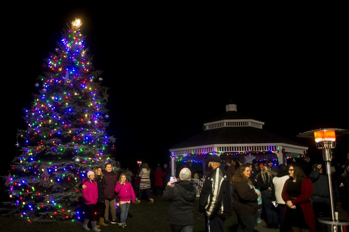 People take photos in front of the Christmas tree after it was illuminated on Saturday, Nov. 24, 2018, in downtown Coleman. (Katy Kildee/kkildee@mdn.net)
