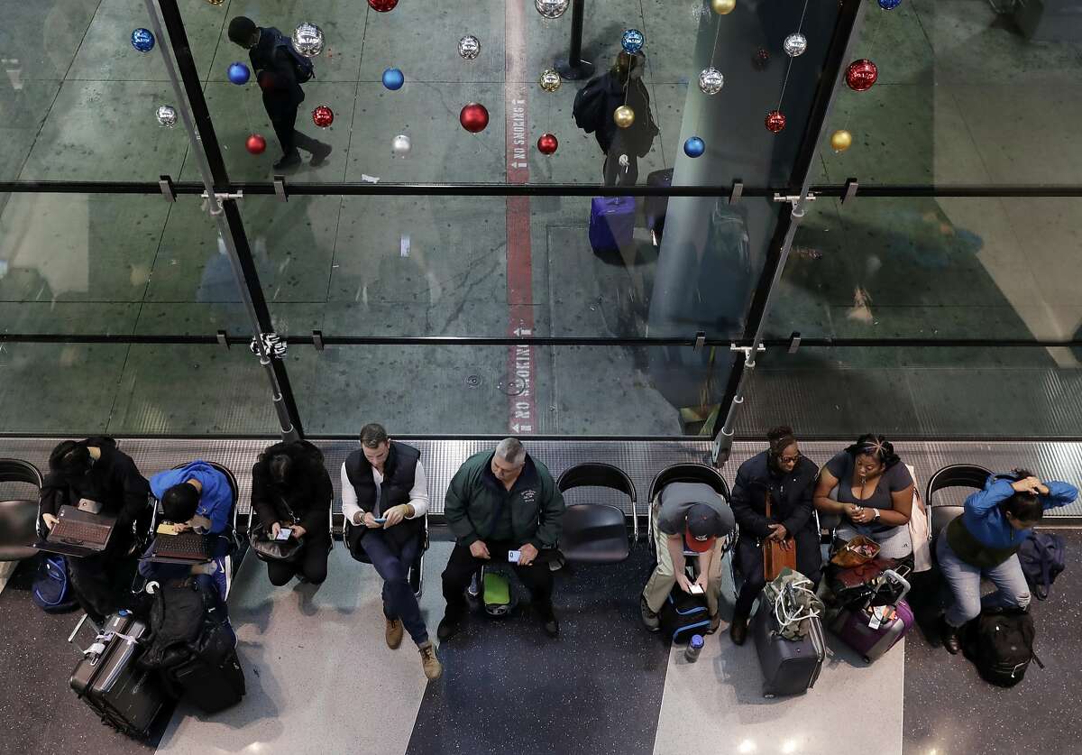 Passengers sit as they wait for their flight at O'Hare airport in Chicago, Sunday, Nov. 25, 2018. More than 700 flights canceled as blizzard warning takes effect in Chicago.