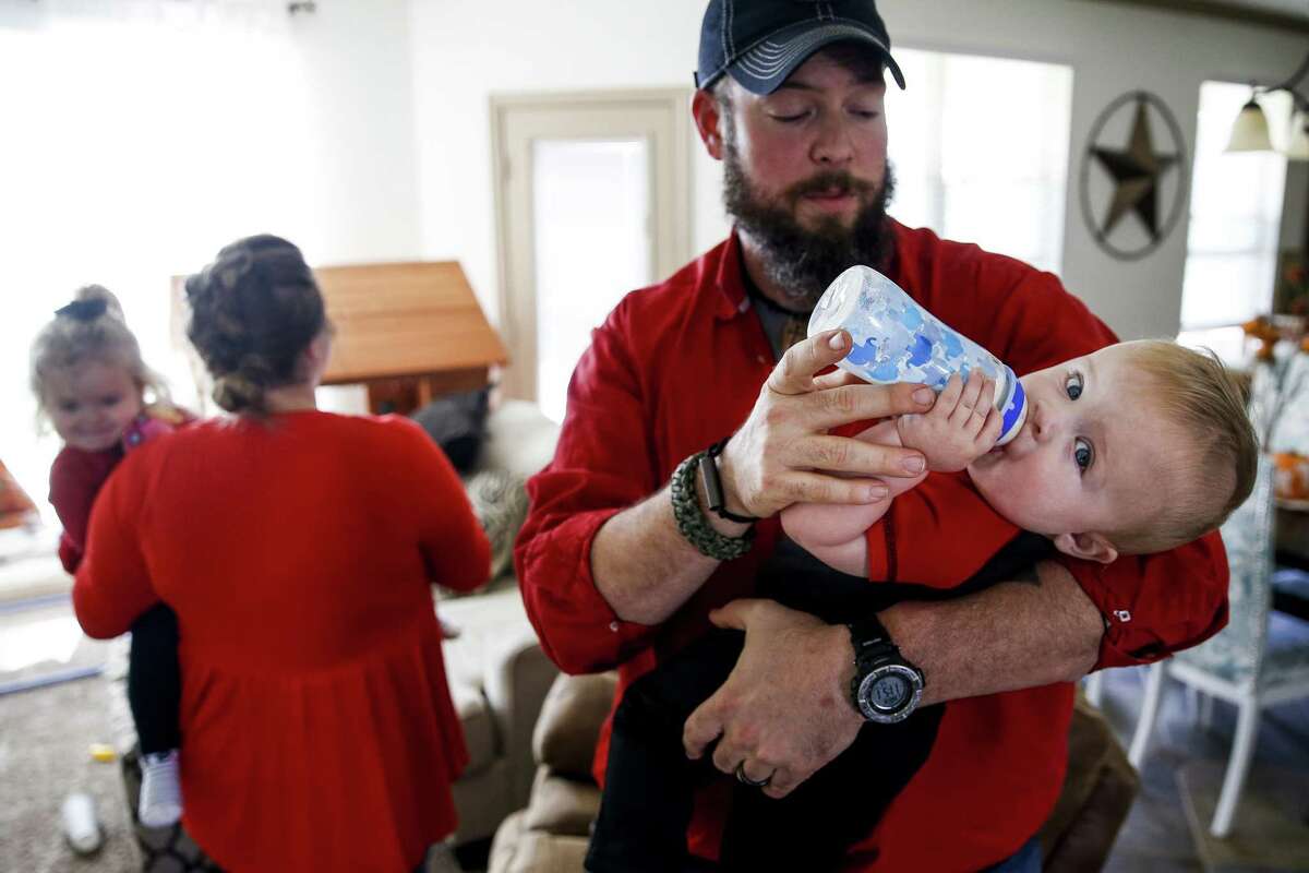 Dillon Bright feeds his nine-month-old son, Mason Bright, a bottle as Melissa Bright holds her daughter, Charlotte Bright, 2, in the background Saturday, Nov. 3, 2018, in Tomball. Child Protective Services is facing sanctions after improperly removing the Bright's children from their home after Mason fell and fractured his skull when he was five months old.