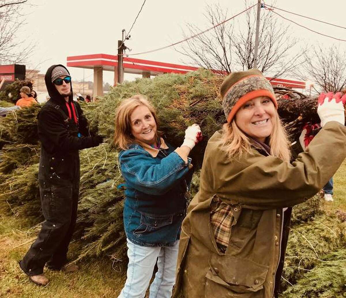 Circuit Judge Kyle Napp, in front, and Ruth Reeves, a therapist with Chestnut Health Systems, help unload a truckload of trees for the Lyons Christmas Tree lot in Edwardsville. The Madison County Drug Court staff helped with the project as a community service. Behind Reeves is one of the drug court defendants.