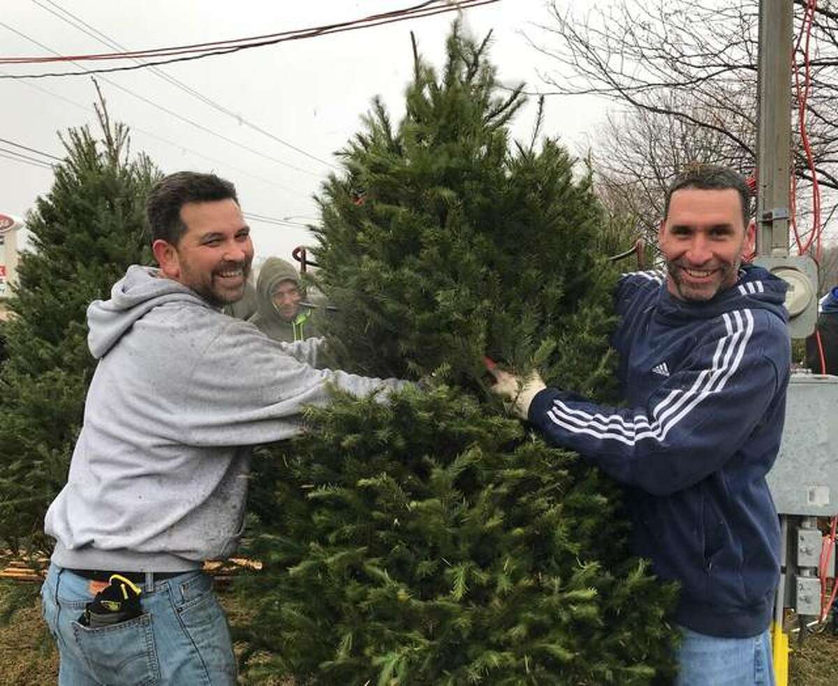 Kevin McKee, right, and Mike Wilkinson, left, help unload Christmas Trees for the Lions Club Christmas tree lot in Edwardsville. They are members of the Madison County Drug Court team, which helped the club as a community service project.