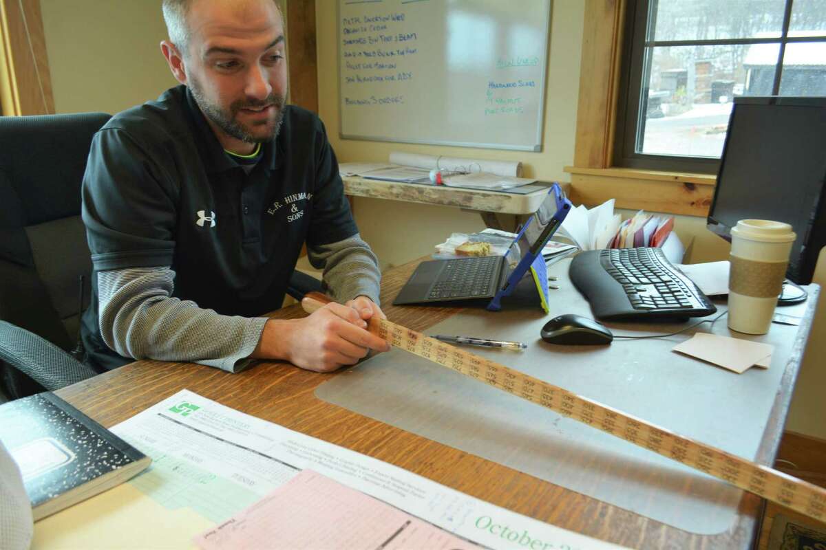 Patrick Sullivan, Hinman & Sons lumber mill manager, shows how a grading stick helps workers calculate how many board feet are contained in a log.
