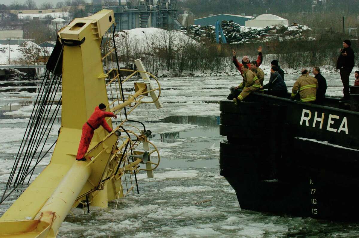Times Union Staff Photo by Skip Dickstein.      Rescue operations are in full swing after a ship overturned in the Port of Albany, New York December 9, 2003. The accident occurred when loading two GE turbines on to the Dutch Registry ship with a Russian crew of 18. Three members of the crew are still missing. A crew member in orange waves his hand for rescue from the front mast of the Stellamare in the Port of Albany.