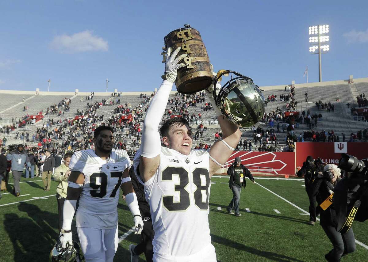 Purdue’s Brennan Thieneman holds up the Old Oaken Bucket after Purdue defeated Indiana 28-21 on Saturday.
