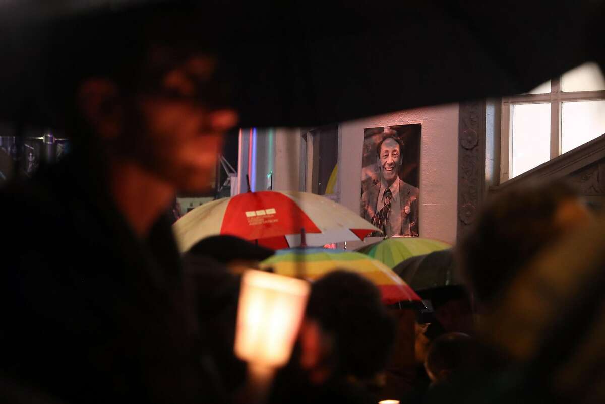 A photograph of Harvey Milk hangs above the crowd during gathering before annual candlelight walk from The Castro to City Hall in memory of Harvey Milk and Mayor George Moscone, who were slain 40 years ago in San Francisco, Calif.. Photographed on Tuesday, November 27, 2018.