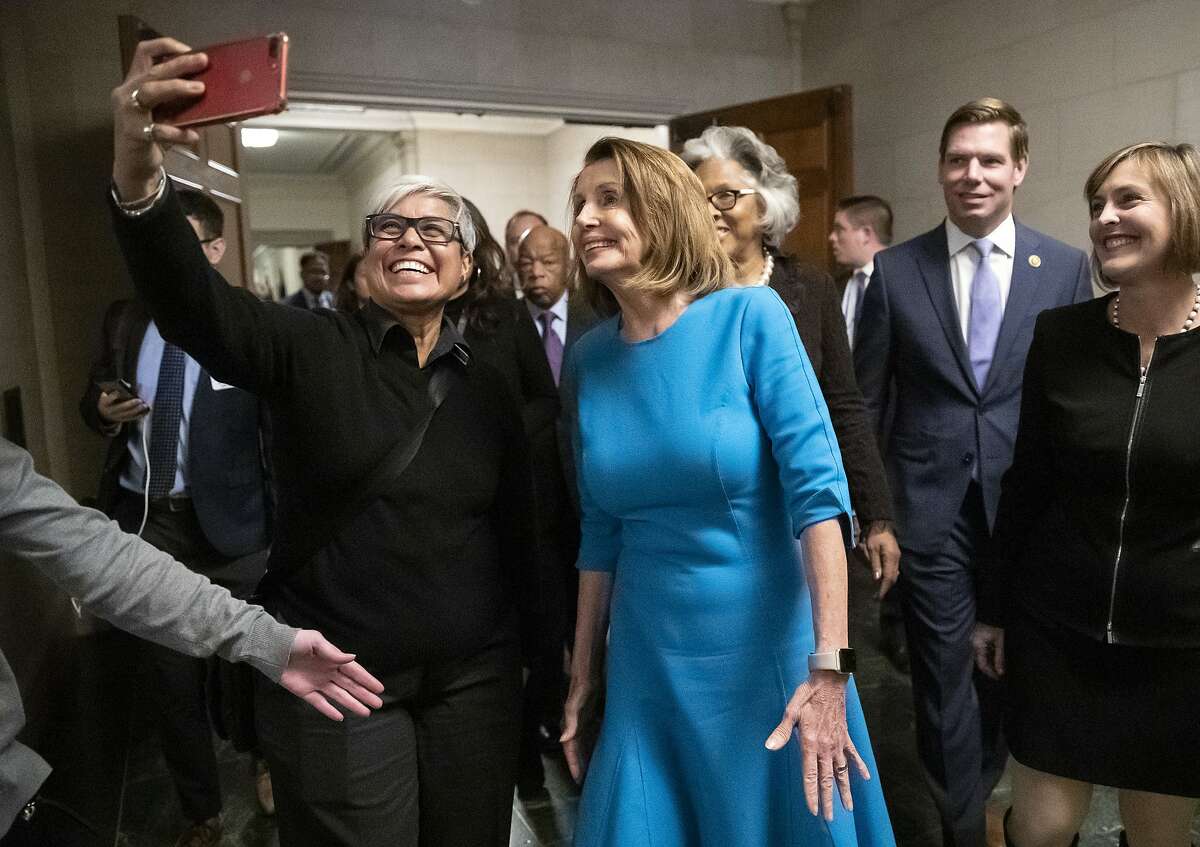 Carmen Guzman, left, a former congressional staffer from McLean, Va., snaps a selfie with Democratic Leader Nancy Pelosi of California, center, as she emerged victorious from the House Democratic leadership elections as the choice for speaker of the House when her party takes power as the majority in the 116th Congress, on Capitol Hill in Washington, Wednesday, Nov. 28, 2018. She still faces a showdown vote for House speaker when lawmakers convene in January. (AP Photo/J. Scott Applewhite)
