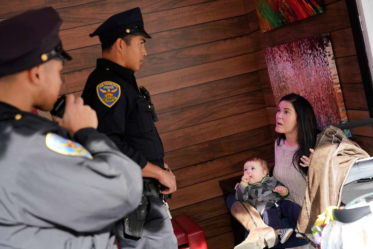 Natalie West (right) kisses her 9-month old son Seven Snodgrass (second from right), both of Eureka, as she holds him on her lap as she discusses the theft of her wallet out of her baby''s stroller with Officer Jason Castro (second from left) and Officer Gordon Wong (left) at the Union Square ice skating rink on Monday, November 26, 2018 in San Francisco, Calif.
