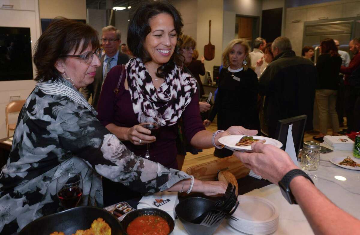 Sharon Kurtzman of Norwalk and Yvette Edgecome of Westport enjoy pork tenderloin from The Spread during the 2nd Annual Cooking for Charity Thursday, November 29, 2018, at Aitoro Appliance in Norwalk, Conn. Guests were able to sample food and beverages served by local restaurants chefs cooking right in Aitoro's showroom kitchens. Proceeds benfit the Human Services Council and the Norwalk Rotary Club. There was an amazing selection of Chance Auction Items that total over $5,000.