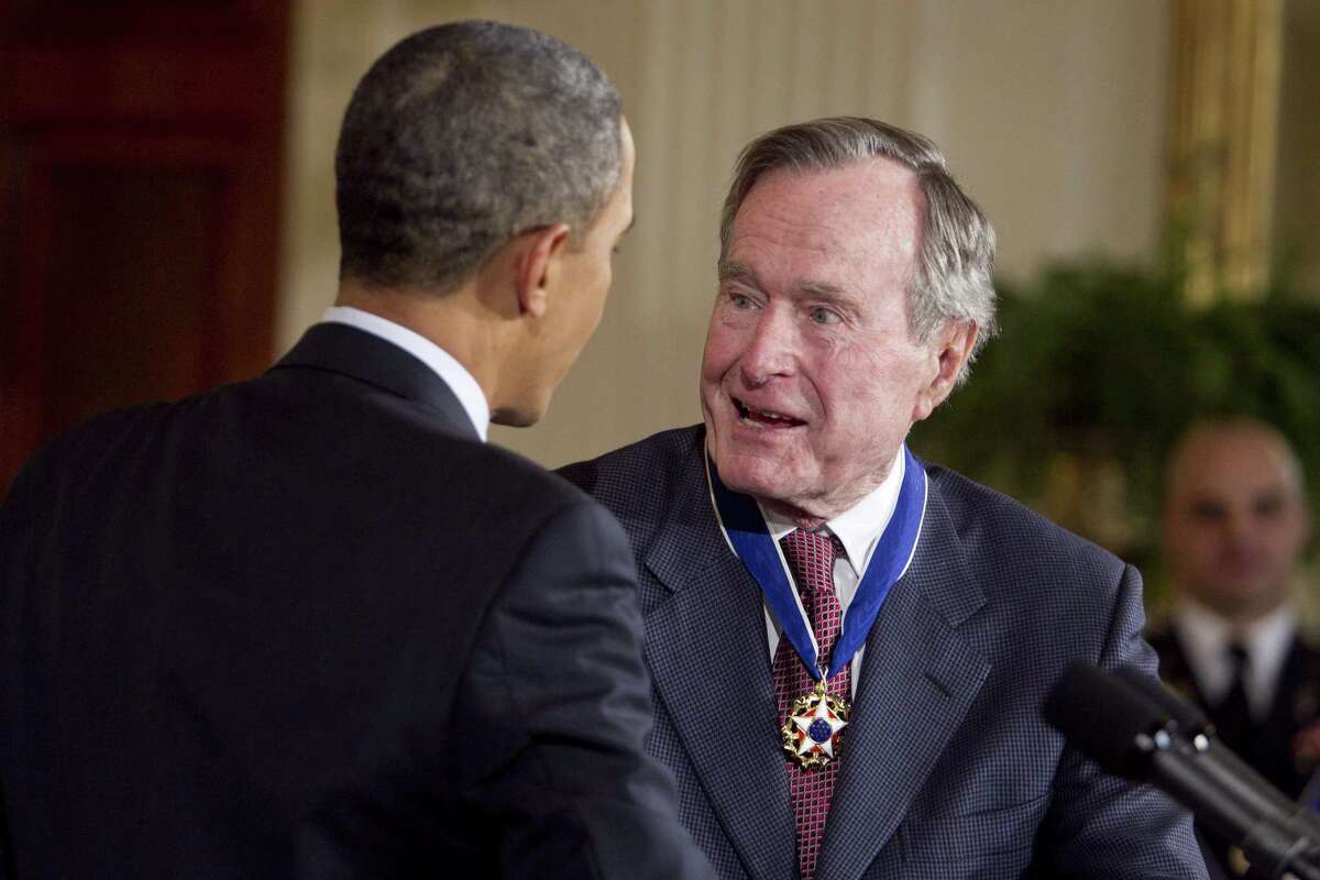 FILE: Former U.S. President George H. W. Bush is awarded the Presidential Medal of Freedom from U.S. President Barack Obama at the White House in Washington, D.C., U.S., on Tuesday, Feb. 15, 2011. George H.W. Bush, the U.S. president who fashioned a restrained response to the Soviet Union?’s collapse and assembled the multinational coalition that liberated Kuwait from an Iraqi invasion, hoping that would be a model for ?“a new world order,?” has died. He was 94. Photographer: Andrew Harrer/Bloomberg