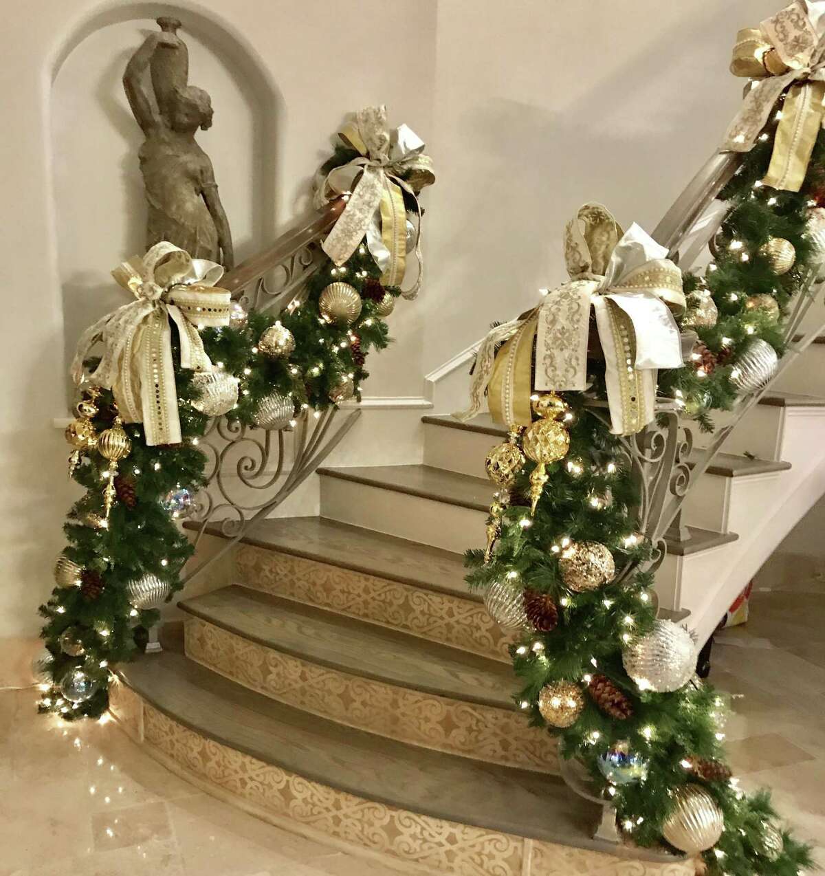 This stair rail is decorated with heavy swags of garland filled with lights, ornaments and big metallic ribbon.