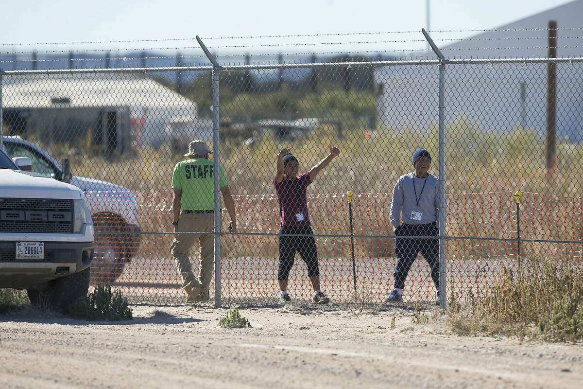 In this Nov. 15, 2018 photo provided by Ivan Pierre Aguirre, migrant teens held inside the Tornillo detention camp smile at protestors waving at them outside the fences surrounding the facility in Tornillo, Texas. The Trump administration announced in June 2018 that it would open the temporary shelter for up to 360 migrant children in this isolated corner of the Texas desert. Less than six months later, the facility has expanded into a detention camp holding thousands of teenagers - and it shows every sign of becoming more permanent. (Ivan Pierre Aguirre via AP)