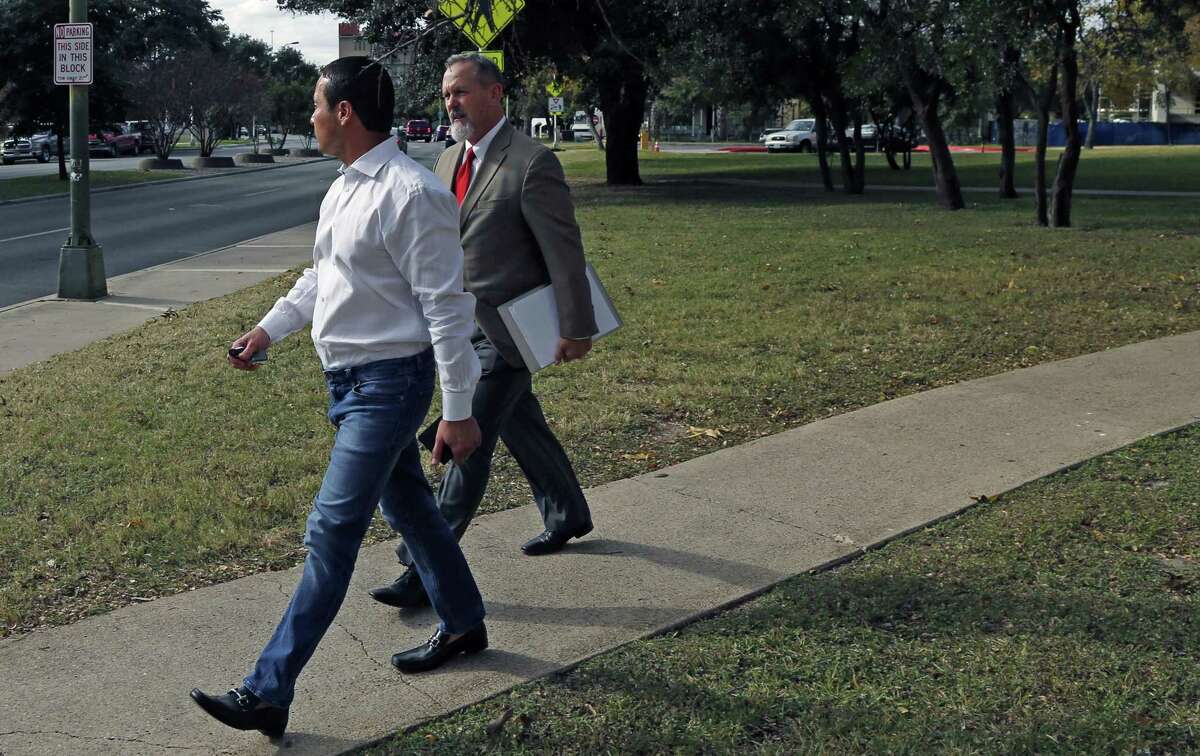 Brian Alfaro, in foreground, did his best to avoid to being photographed as he left the San Antonio federal courthouse. At right is his attorney Mike McCrum. Alfaro was indicted last week on eight counts of mail fraud allegedly related to defrauding investors in oil and gas ventures.