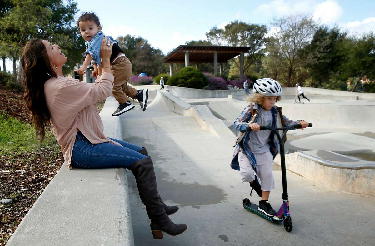 Kelli Peterson holds Che, 1, while her oldest son Kin, 5, whizzes past at a skatepark in San Rafael, Calif. on Saturday, Dec. 1, 2018.