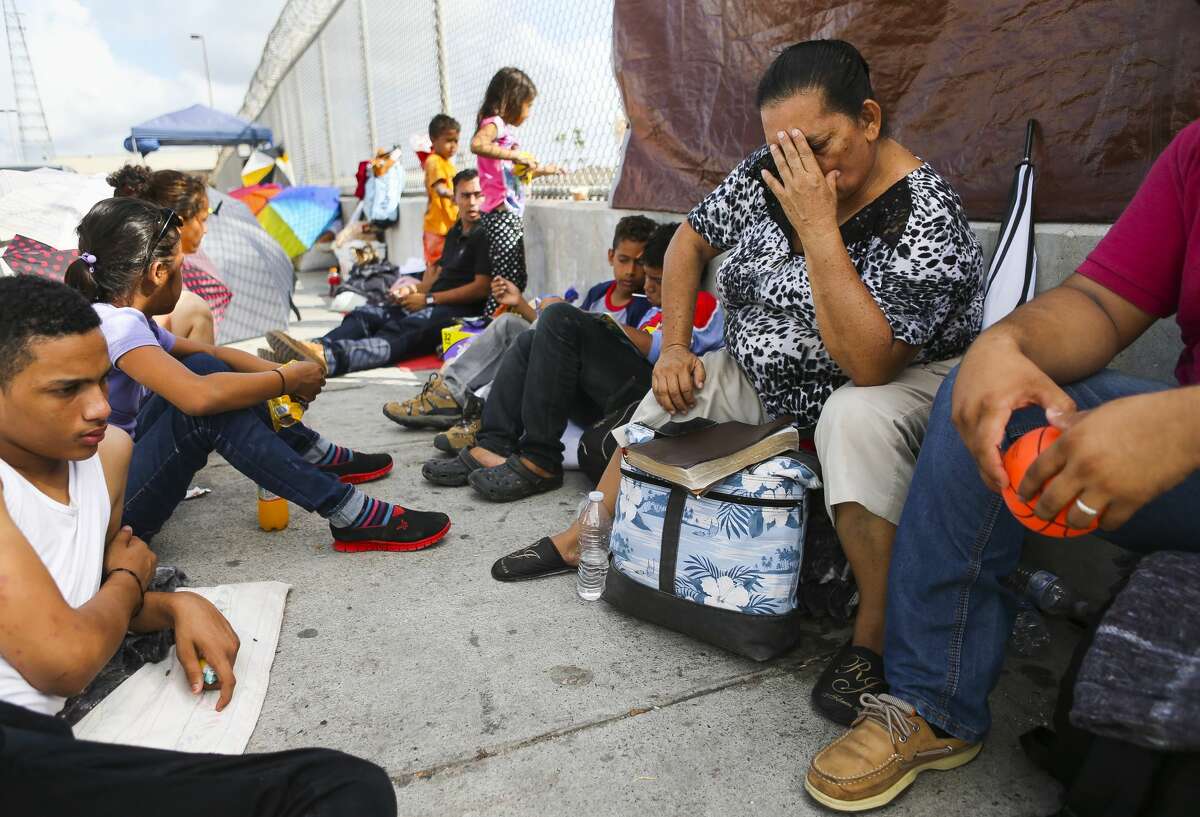 Isabel Flores (right) prays as members of her family and another Honduran family hoping to seek asylum in the United States wait on the Mexican side of the middle of the Brownsville & Matamoros Express International Bridge for their fourth day in a row, Wednesday, June 27, 2018 in Brownsville. The families are hoping that they can pass together into the country and ask for asylum after fleeing violence at home. ( Mark Mulligan / Houston Chronicle )