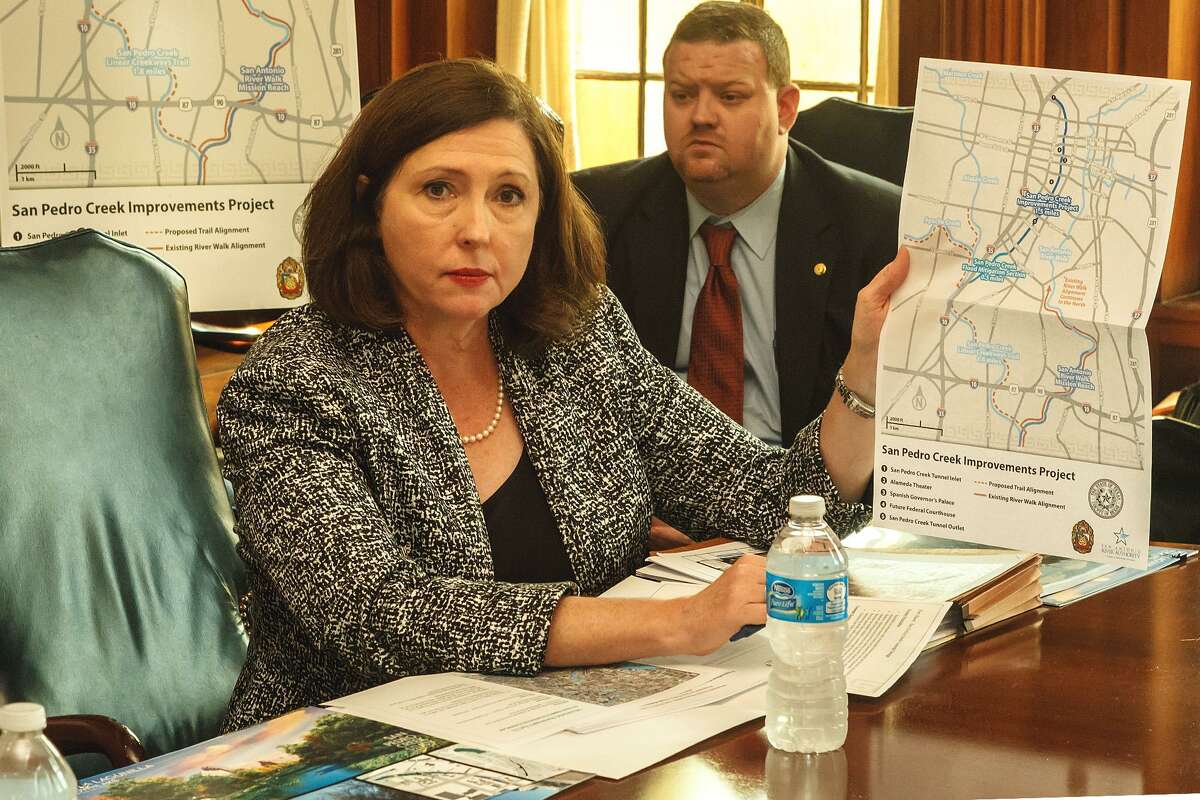San Antonio River Authority General Manager Suzanne Scott, with engineer Russell Persyn in the background, shows a map of proposed improvements to San Pedro Creek in 2013.