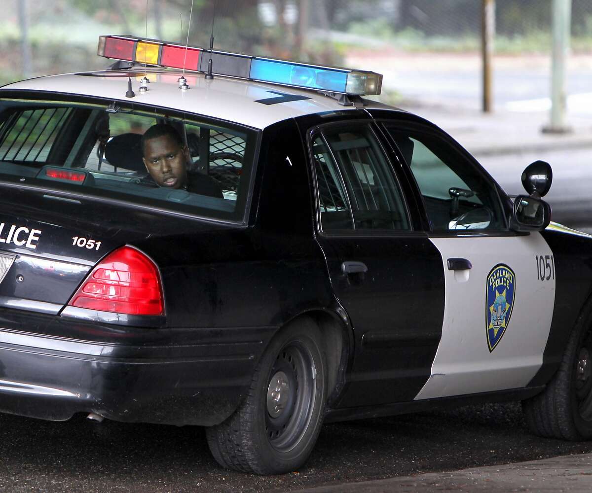 A suspect waits in the police car after being arrested for burglary and position of weapons at the intersection of High Street and Gravenstein, Thursday March 15, 2012, in Oakland, Calif.