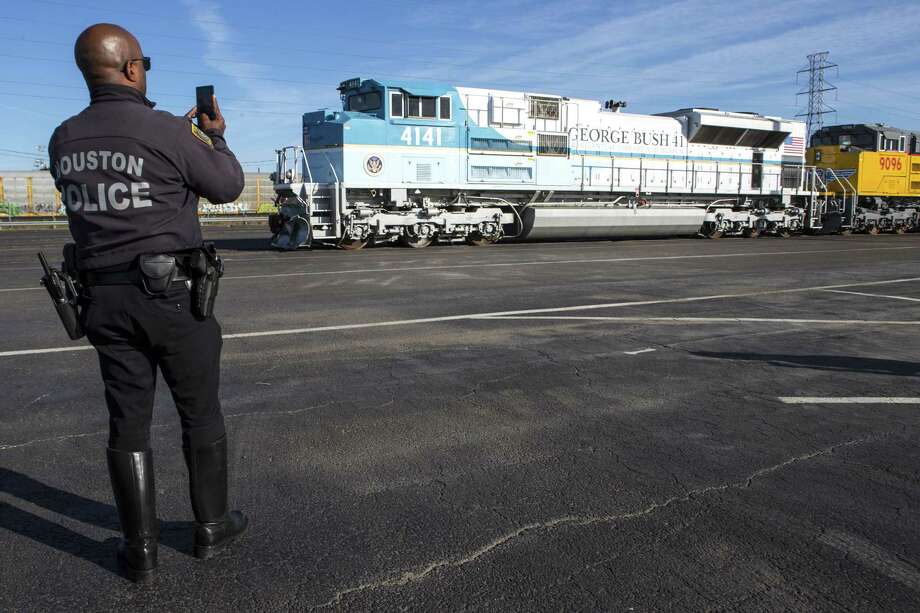 A Houston Police officer takes a photo of the Union Pacific 4141 George Bush 41 Locomotive as it is prepared for service on Dec. 3. UP 4141 will pull Union Pacific's passenger rail cars and the bagage car The Council Bluffs, which will carry former President George H.W. Bush's remains to College Station for burial. Photo: Brett Coomer, Houston Chronicle / Staff Photographer / © 2018 Houston Chronicle