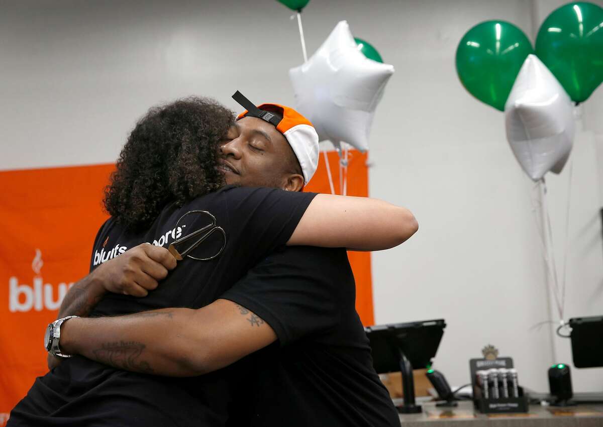 Alphonso Blunt hugs his business partner Brittany Moore after cutting the ribbon to open the Blunts + Moore cannabis dispensary in Oakland, Calif. on Thursday, Nov. 29, 2018, the first dispensary to open through the city's cannabis equity program.