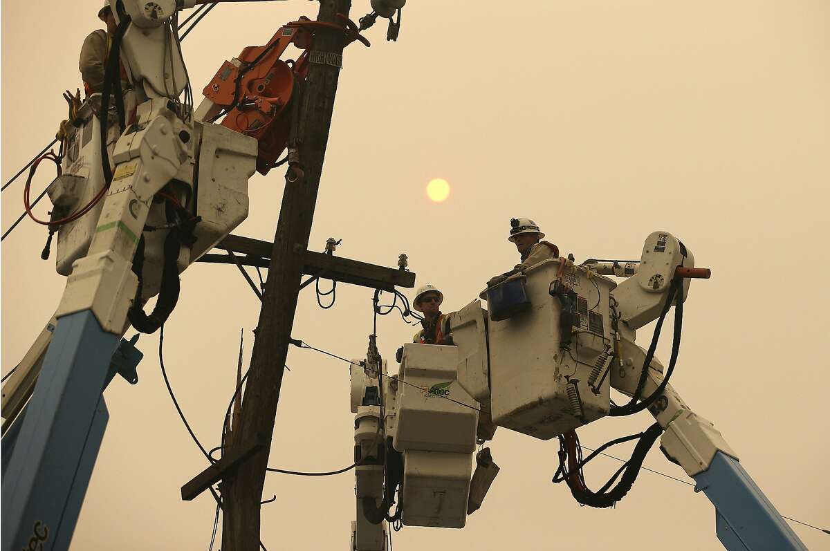 FILE - In this Friday, Nov. 9, 2018 file photo, Pacific Gas & Electric crews work to restore power lines in Paradise, Calif. A U.S. judge overseeing a criminal case against Pacific Gas & Electric Co. asked the utility Tuesday, Nov. 27, 2018, to explain any role it may have played in a massive wildfire that destroyed a Northern California town. Judge William Alsup in San Francisco directed PG&E in a court filing to respond to a series of questions about power line safety and wildfires. (AP Photo/Rich Pedroncelli, File)